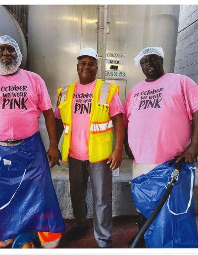 Three men all wearing t-shirts that says "In October We Wear Pink"