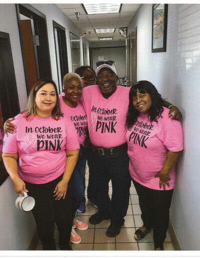 Three women all wearing t-shirts that says "In October We Wear Pink"