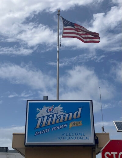 American flag flying above a sign that says "Welcome to Hiland Dallas"
