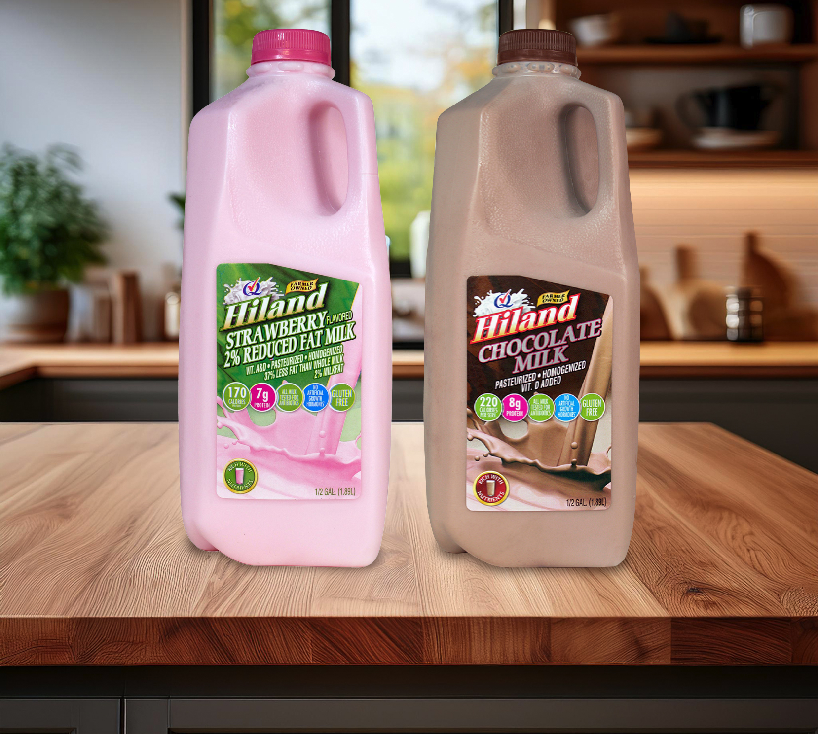 Two half-gallon bottles of Hiland Strawberry 2% Reduced Fat Milk and Hiland Chocolate Milk sit on a wooden kitchen counter. The pink strawberry milk jug features a green label highlighting its nutritional benefits, while the chocolate milk jug has a brown label showcasing its rich, creamy texture. A modern kitchen with warm lighting and wooden shelves is visible in the softly blurred background.