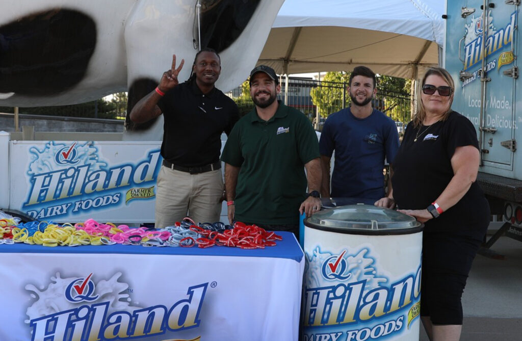 Four smiling employees outdoors at a Hiland Dairy community event