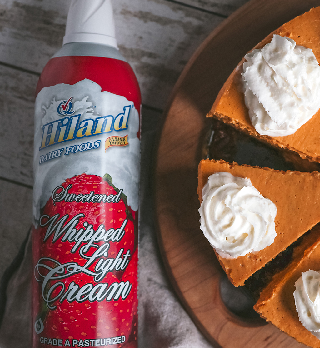 Pumpkin Cheesecake made with Hiland Dairy Cream Cheese and Sour Cream next to a can of Hiland Whipped Cream