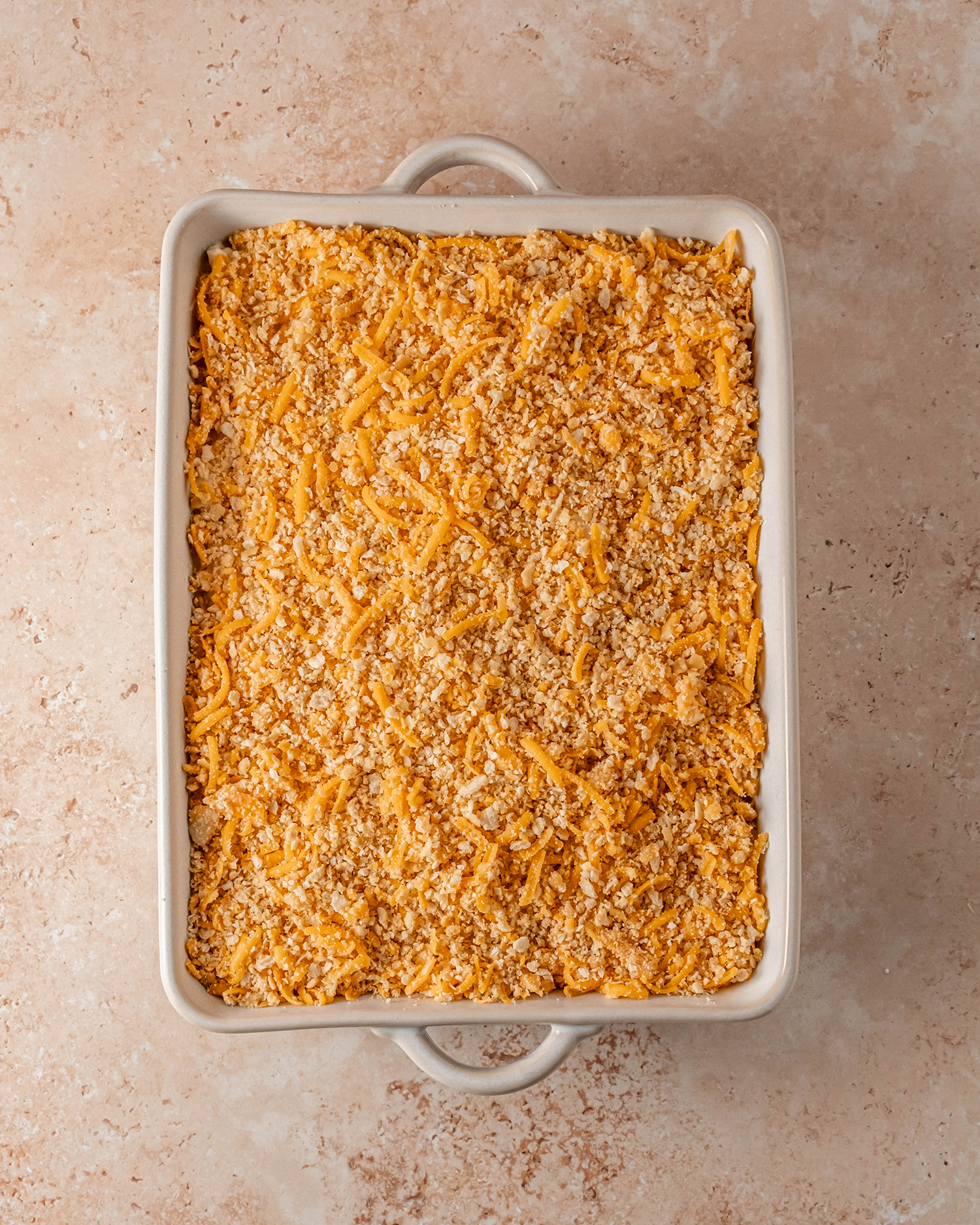 Golden cheesy potato casserole with all ingredients in the baking dish, ready to go into the oven.