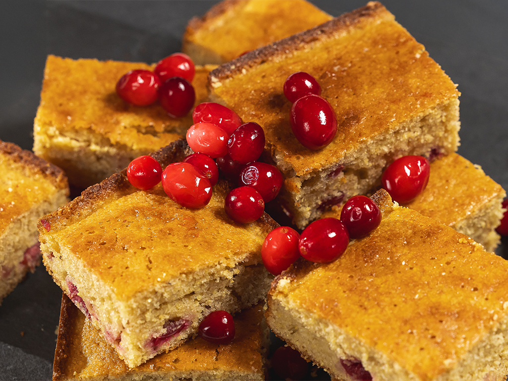 Golden slices of cranberry cornbread topped with fresh, vibrant cranberries.