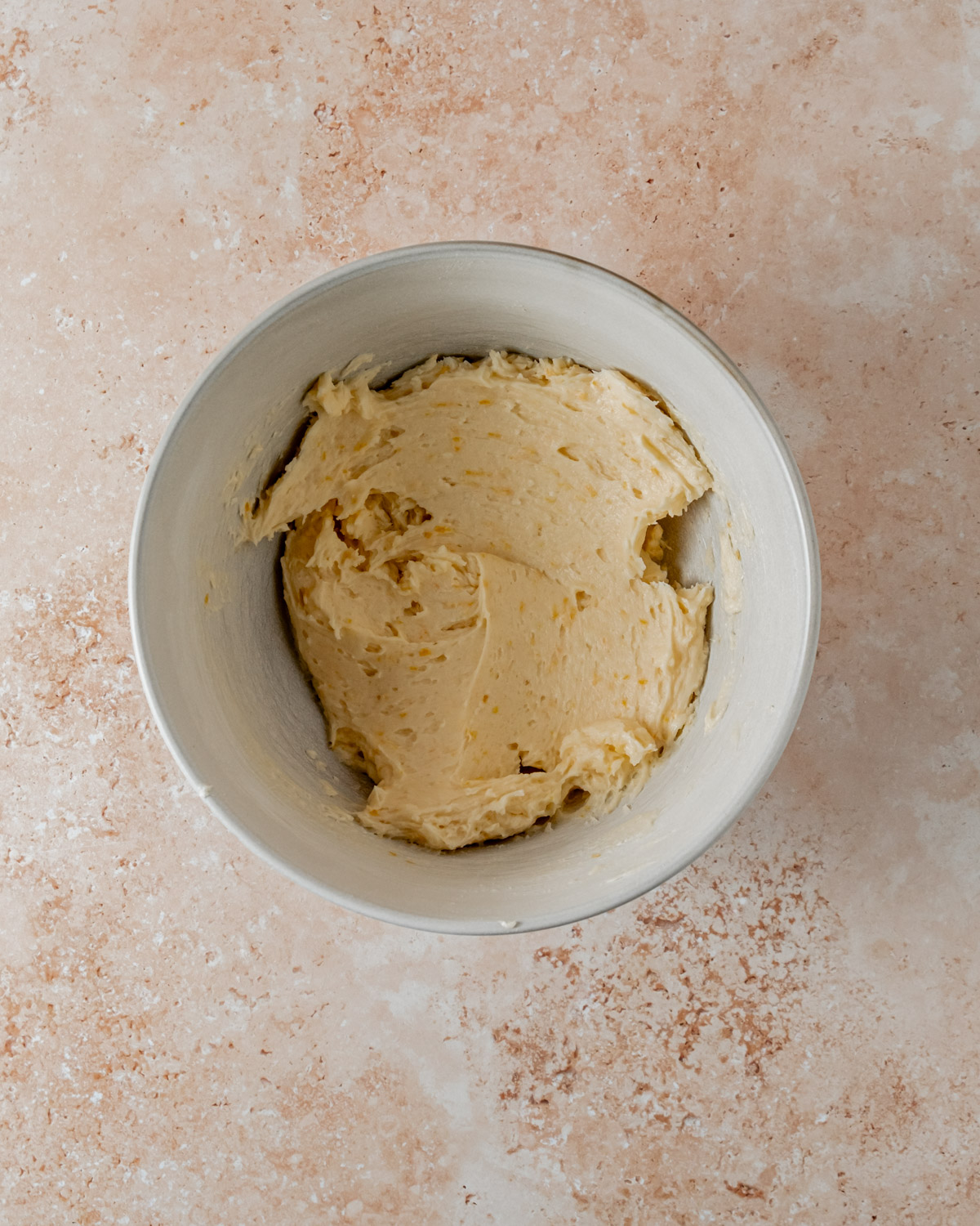 Bowl with smooth and creamy orange shortbread cookie dough, slightly tinged with orange from the zest, ready for shaping.