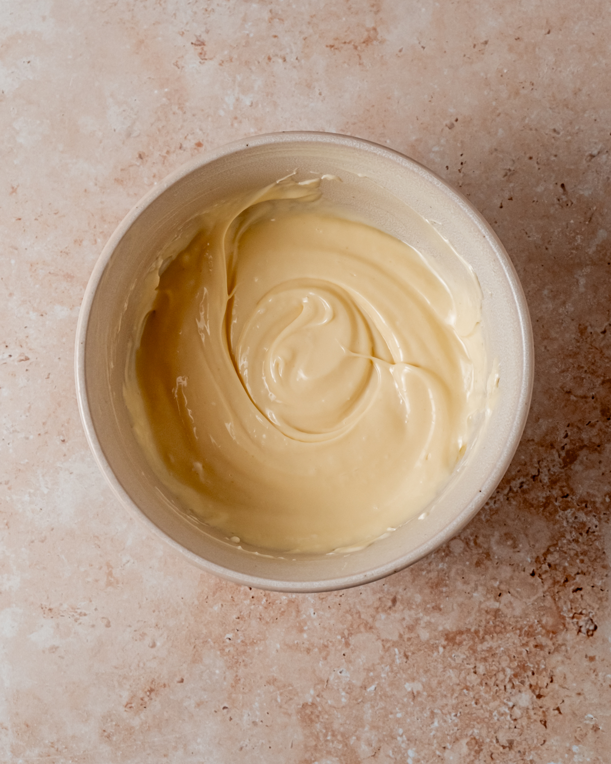 A bowl of thick and creamy yellow filling, swirled to a smooth finish, ready for use in pastries.