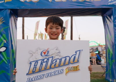 young boy holding a Hiland Dairy sign Tyler, TX under a banner that reads "Ag-Venture"